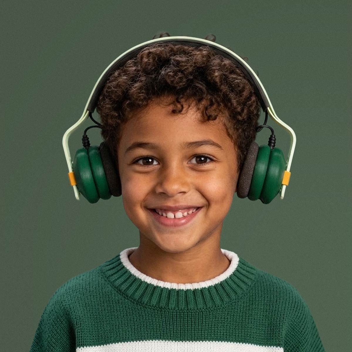 Boy smiling while wearing Kibu Woodland Walk headphones with green ear cups and a mint headband